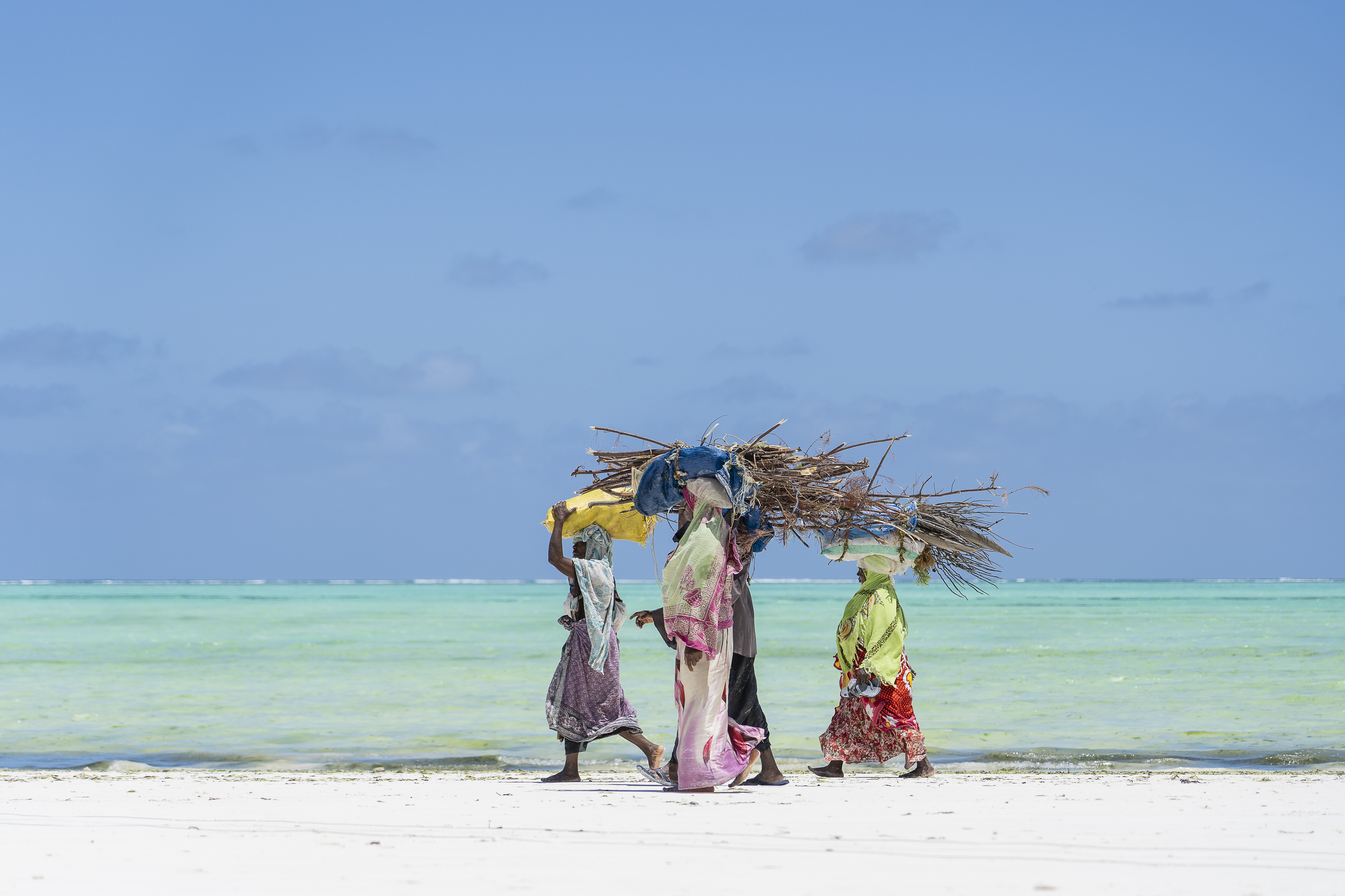 Zanzibari women walking along a turquoise-water beach